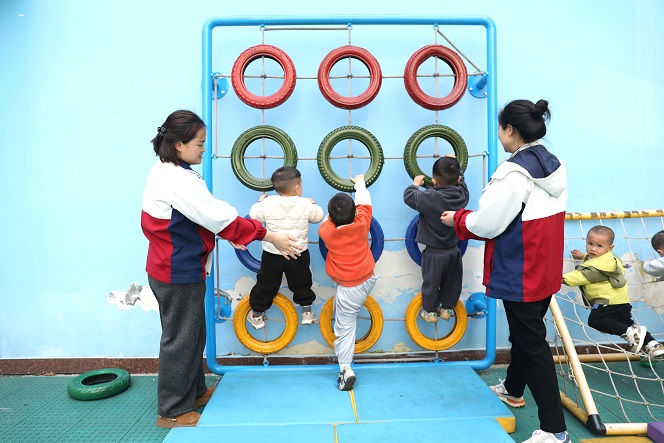 4月24日，天柱县妇幼保健院托育中心内，保育员引导孩子们参与轮胎攀爬活动。.JPG